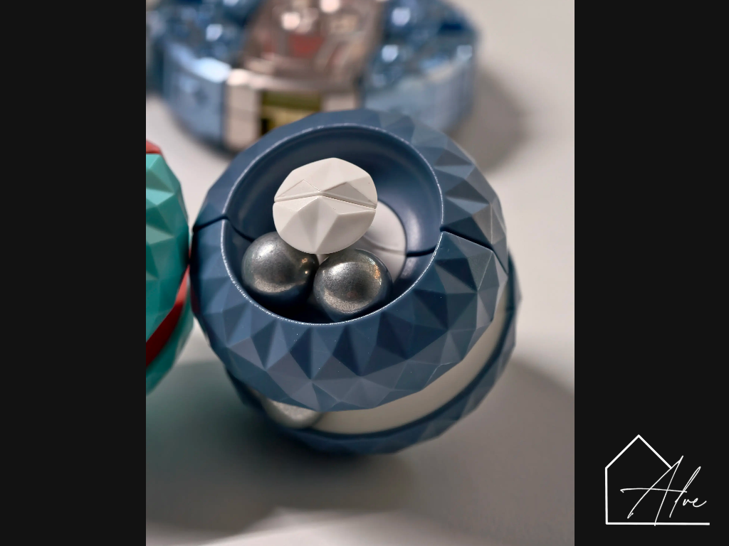 Blue and white sphere fidget ball opened to show three steel beads inside the internal track